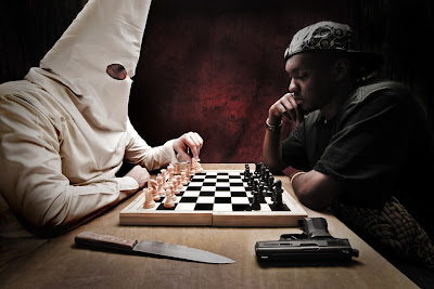 Hvid Ku Klux Klan mand spiller skak mod sort mand, mens våben ligger på bordet