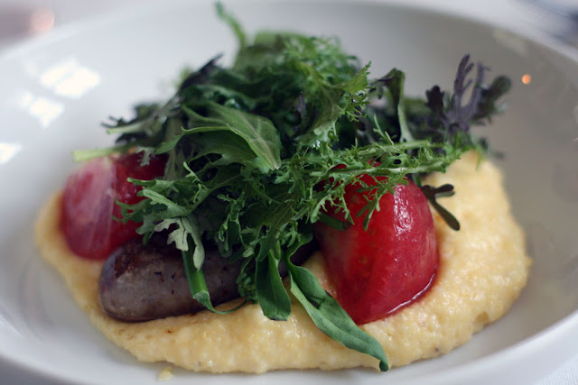 House Sausage on a bed of Gruyere Polenta, confit tomatoes, rapini, mustard greens