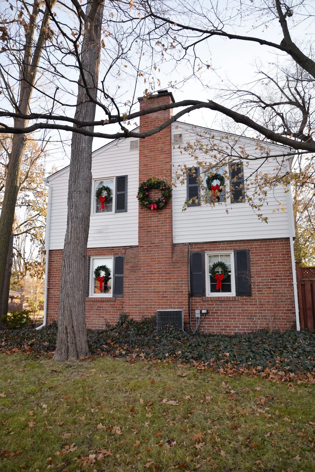 wreath on chimney, wreaths on windows, Christmas wreaths on exterior windows, Colonial house with wreaths in windows, wreath on chimney