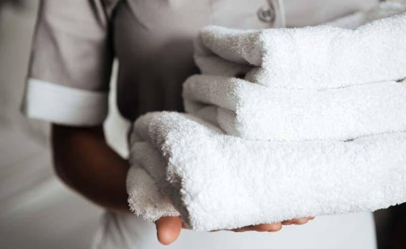 Close up of a young hotel maid holding clean folded towels