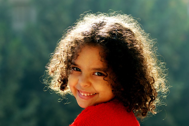 NAMC Montessori circle of inclusion developing organized work. girl with curly hair smiling at camera