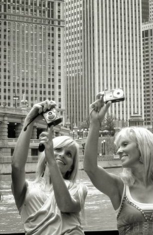 Two women taking photos of skyscrapers in Chicago