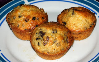 three cornmeal and flour muffins incorporating hibiscus flowers and mulberries made without butter presented on a plate