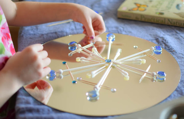 Winter STEM- Build A Snowflake Tinker Tray.  Use loose parts to build snowflakes.  Explore radial symmetry as you incorporate math, science, fine motor work, and creativity in this activity for preschoolers, kindergartners, and elementary school.