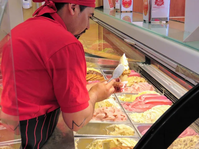 Man preparing an ice cream cone at Helados Jauja in Bariloche Argentina