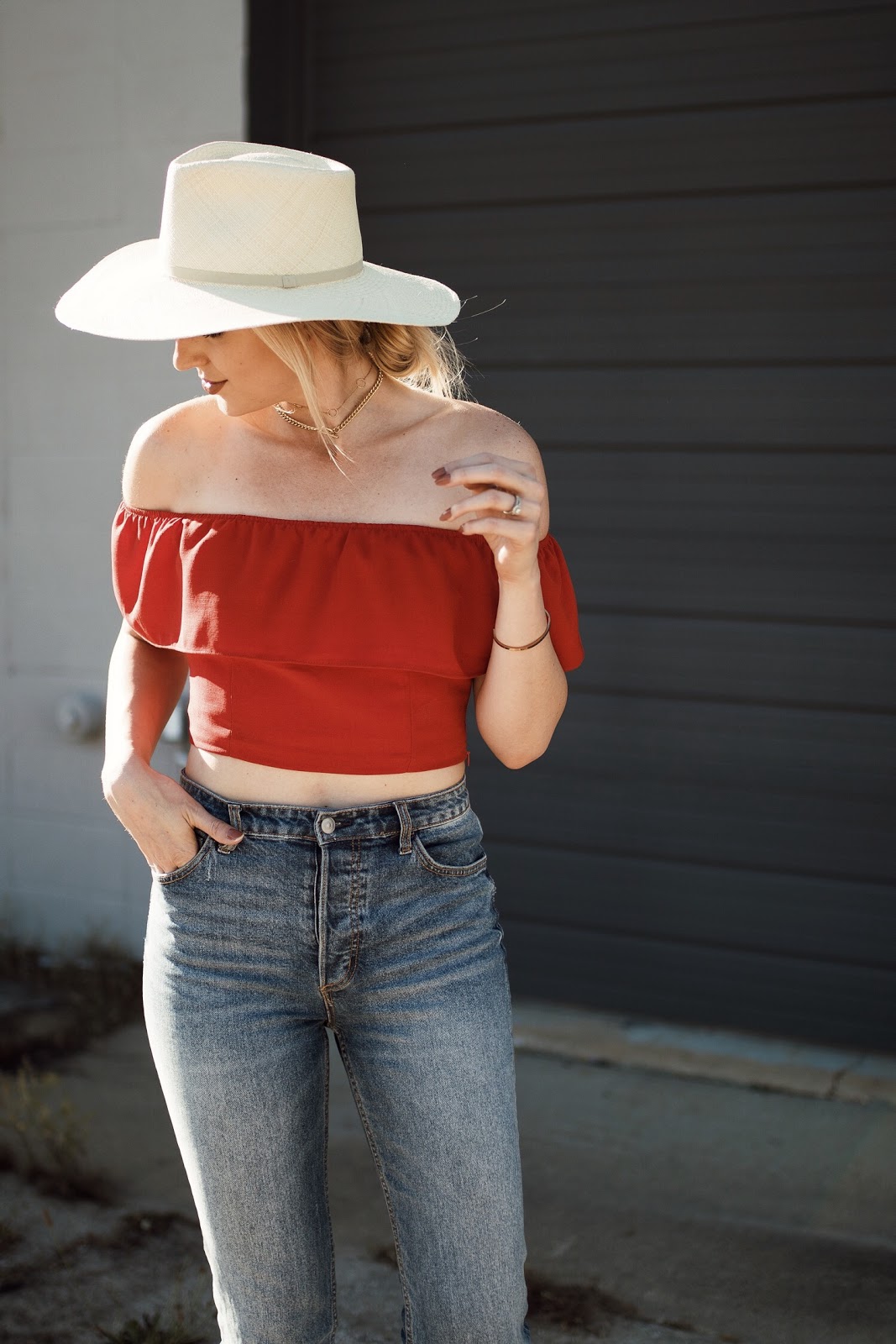 red off-the-shoulder top, high-waisted denim, straw hat