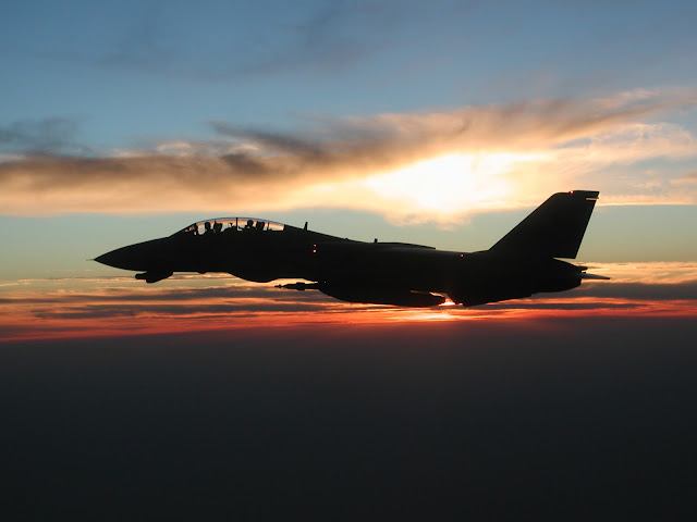 F-14D infligh with sunset behind it.