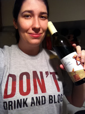 Jen wearing a shirt that reads 'Don't drink and blog' while holding a bottle of wine