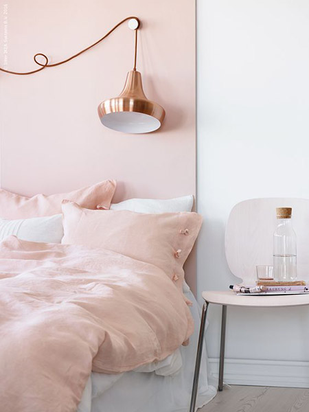 tête de lit rose pastel et lampe cuivre
