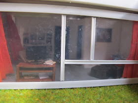View through the window of a 1/48-scale mid-century modern house, showing a studio in white with accents of orange and brown.