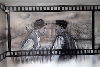 Czarno-biały obraz Obraz wykonany na ścianie w czarno-bieli, artystyczne malowanie ściany we wzór z filmu "Sami Swoi" czarno-biały mural