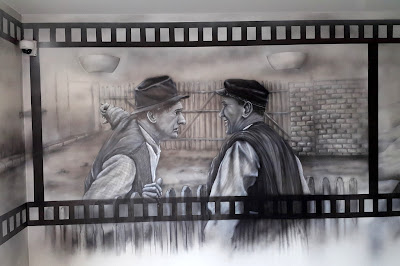 Czarno-biały obraz Obraz wykonany na ścianie w czarno-bieli, artystyczne malowanie ściany we wzór z filmu "Sami Swoi" czarno-biały mural