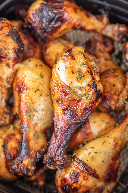 Air Fryer Spicy Chicken Drumsticks Recipe - incredibly easy to make in the air fryer! Chicken drumsticks marinated in Italian dressing, Worcestershire sauce, and hot sauce. SO tender and juicy. Add extra hot sauce to cooked chicken if you like it really spicy. You will never cook chicken drumsticks any other way! Seriously the BEST! #airfryer #chicken #drumsticks #chickendrumsticks chicken drumsticks in air fryer basket