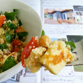 Bowlful and forkful of couscous and haloumi salad in front of a notebook containing pictures and many notes and scribbles.