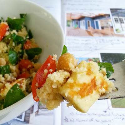 Bowlful and forkful of couscous and haloumi salad in front of a notebook containing pictures and many notes and scribbles.