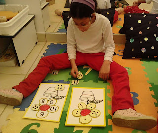 Giovana sentada no tapete colocando as pétalas no segundo tabuleiro do jogo