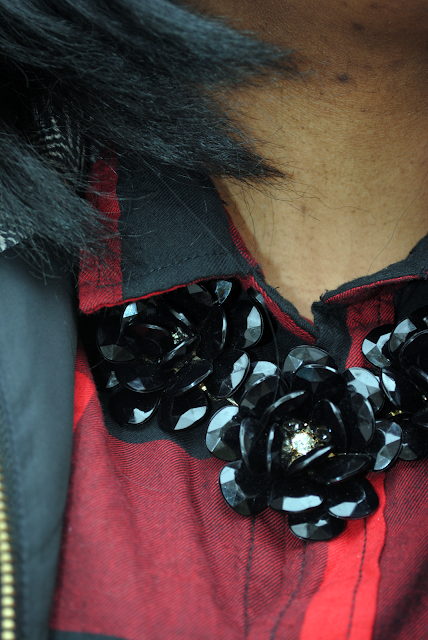 A holiday outfit inspiration post featuring a buffalo plaid shirt, herringbone vest, black pants and black booties.