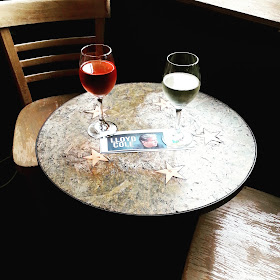 Two glasses of wine on a cafe table with a ticket to a Lloyd Cole concert between them.
