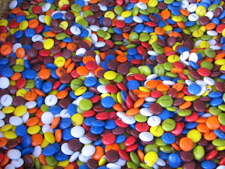 Cientos de "lentejitas" de chocolate de diferente colores: azules, blancos, marrones, amarillos, naranjas, verdes...