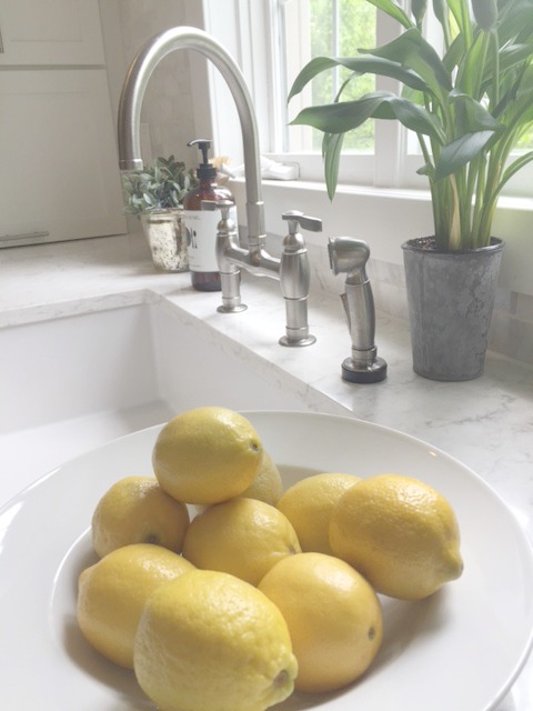 Lemons in a white bowl on a Viatera Minuet countertop in kitchen near farm sink - Hello Lovely Studio.