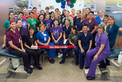 Group picture of dental clinic staff holding large toothbrush