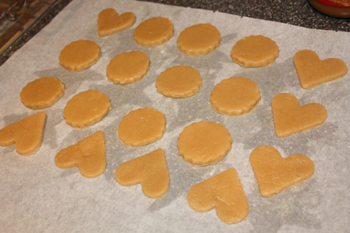 cut out sugar cookie dough on a baking sheet, in heart and circle shapes