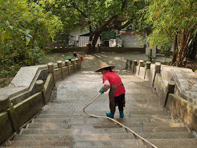 woman spraying water from a hose onto stone steps