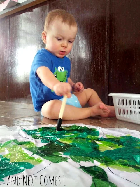 Toddler doing bleeding tissue paper art project for St. Patrick's Day