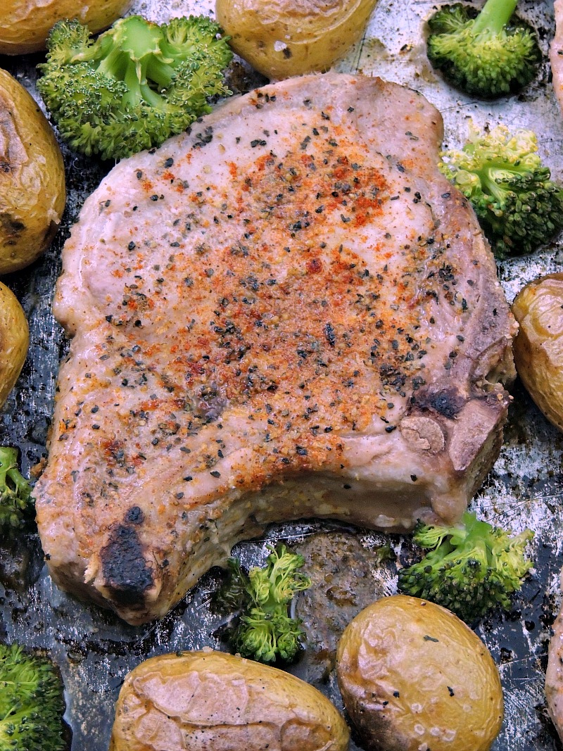 Close up of Sheet Pan Cajun Pork Chops with Potatoes and Broccoli on a metal sheet pan.