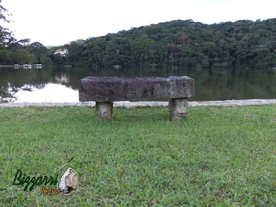 Banco de pedra com pedra folheta em frente ao lago com os muros de pedra.
