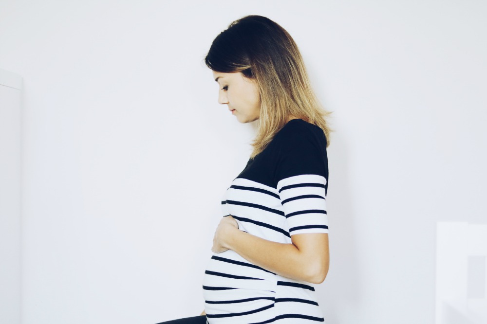 pregnant-woman-wearing-black-and-white-stripy-top-sitting-sideways-looking-downwards