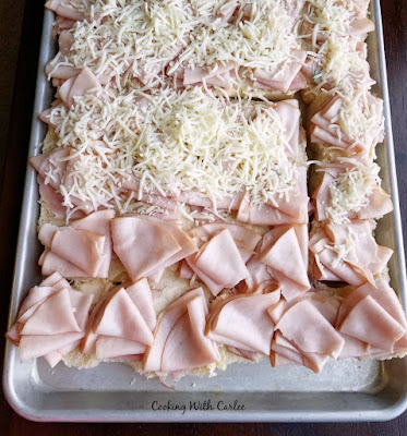 tray of partially assembled sliders with cheese, ham and turkey