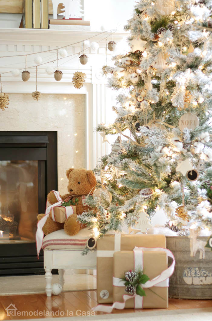flocked christmas tree, wooden ornaments, chalkboard ornaments, galvanized bucket, pinecone and acorn garland, mantel, teddy bear, presents