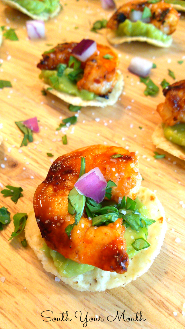Chipotle Shrimp Tostada Bites! Super fun and easy mini tostadas made with tortilla chips, chipotle glazed shrimp and guacamole sprinkled with a confetti of red onion and cilantro.