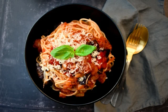 a bowl of spaghetti coated in tomato and roasted red pepper sauce