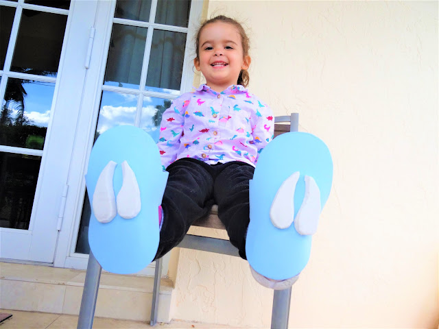 A little girl wearing foam shoes with deer footprints stuck to the bottom.