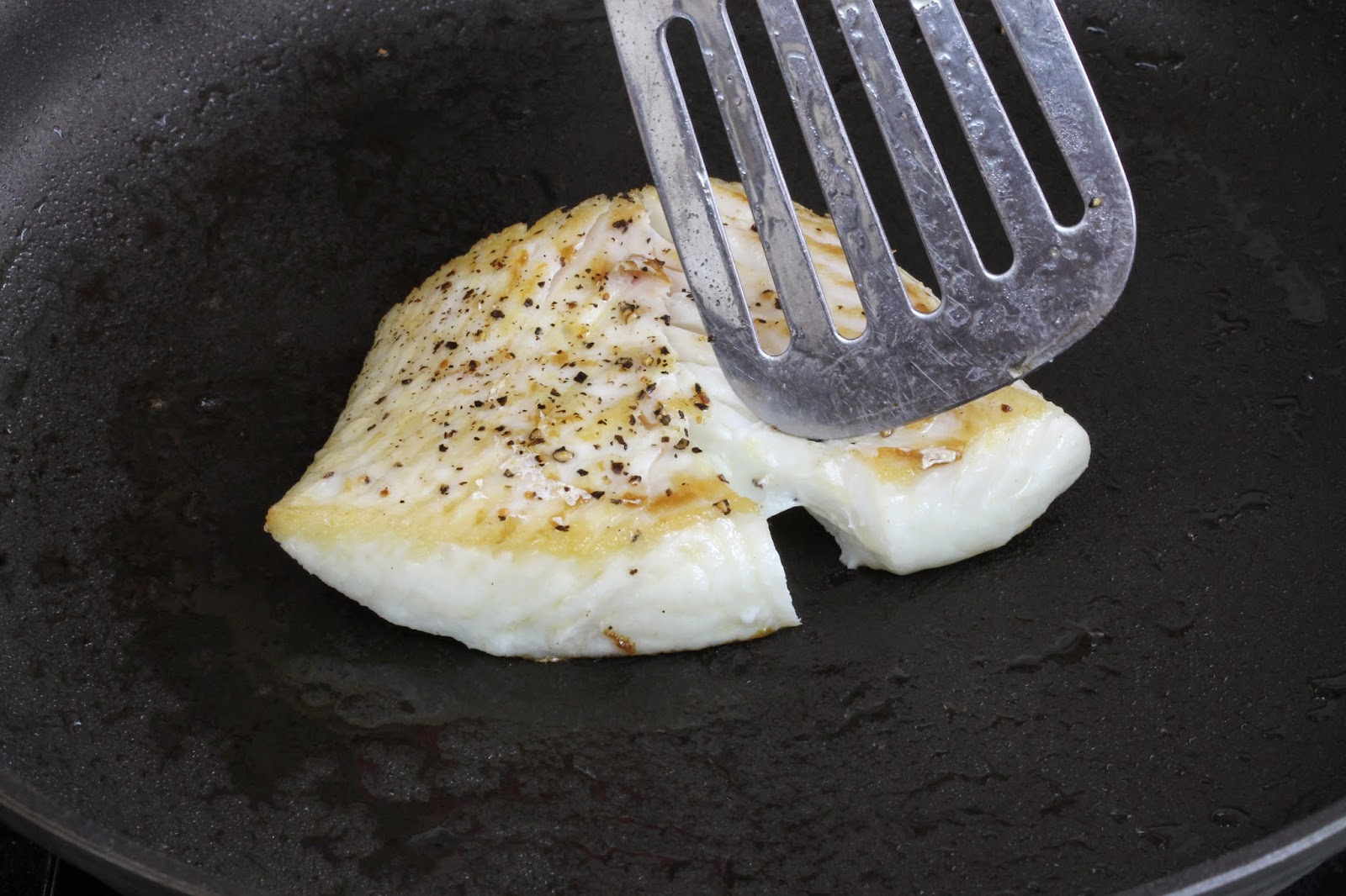 Rachel uses a spatula to check the doneness of the center of the fish filet