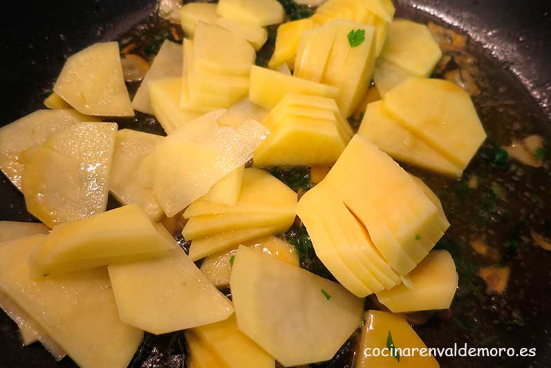 Echando las patatas cortadas finas a la cazuela