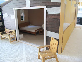 Dry fit of a dolls' house shed kit, with stained weatherboarding taped in place and white sliding door frames fitted.