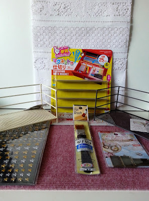 Selection of discount items from Daiso, including a table runner, sticker sheet, wire shelves, a paint brush and a packet of metal crafting frames.