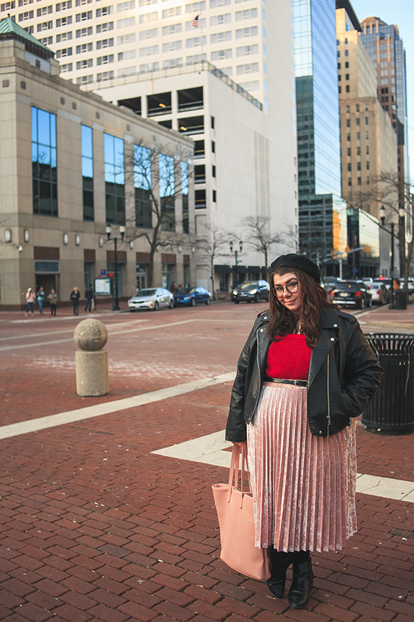An outfit of black beret, black faux leather moto jacket, peter pan collared berry paisley dress, red sweater, pink velvet midi skirt, black tights with red hearts ala polka dots, black heeled chelsea boots and pink tote bag.