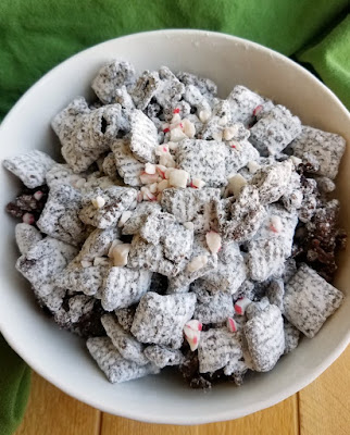 This crunchy, sweet and delicious snack mix is perfect for the holidays. Reindeer chow, or dark chocolate candy cane puppy chow, is perfect for giving and eating! bowl of powder sugar coated dark chocolate and peppermint muddy buddies