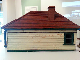 1930s vintage dolls' house bungalow on display in a museum gallery, showing the side.