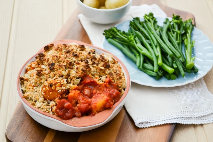 Vegan Tomato Gnocchi Bake with Cheesy Oat Crumble. An easy veggie family bake made with a fresh tomato sauce, gnocchi and a cheesy crumble topping. Serve with baby potatoes and vegetables. www.tinnedtomatoes.com