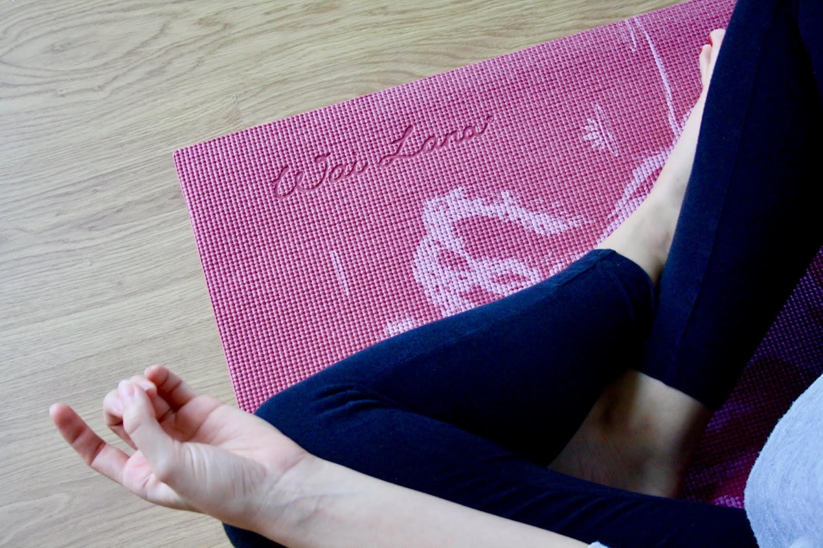 close up of abbey's crossed legs on a yoga mat, her hands in the mudra position