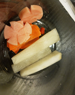 a bowl of finished pickles, showing a red radish slice cut into a flower shape