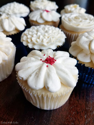 Fluffy, buttery, creamy, sumptuous Italian meringue buttercream is perfect for piping and deliciously decadent for eating too! white cupcakes topped with Italian meringue buttercream flower decorations
