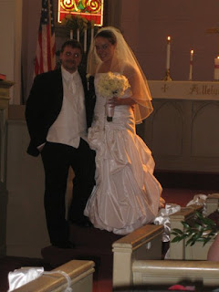 picture of Pat and Kim on their wedding day, in a church Pat in tux Kim in white wedding dress