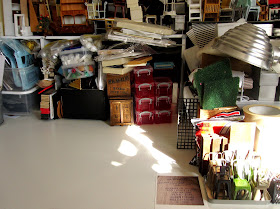 Work table with piles of dolls' house miniature furniture and supplies and a clear space in the middle.