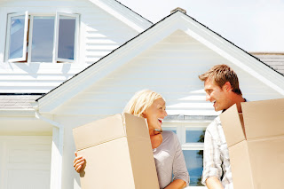 Moving women and man carrying boxes and smiling